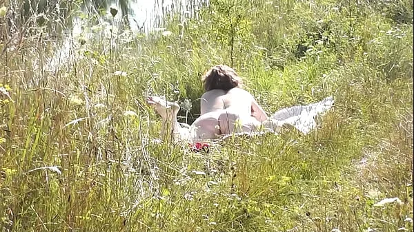 A casual passerby young guy saw a naked Milf sunbathing on river bank. Peeping. Spy camera. Naked in public. Nude beach. Wild beach videos