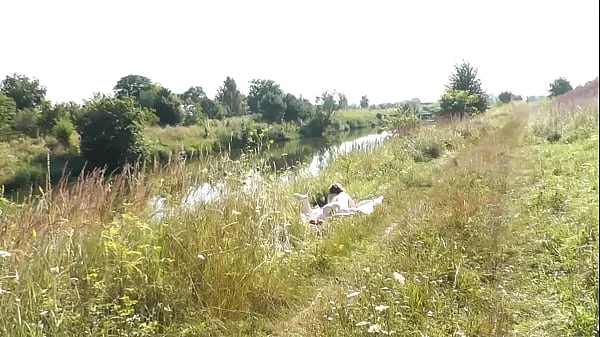 A casual passerby young guy saw a naked Milf sunbathing on river bank. Peeping. Spy camera. Naked in public. Nude beach. Wild beach videos